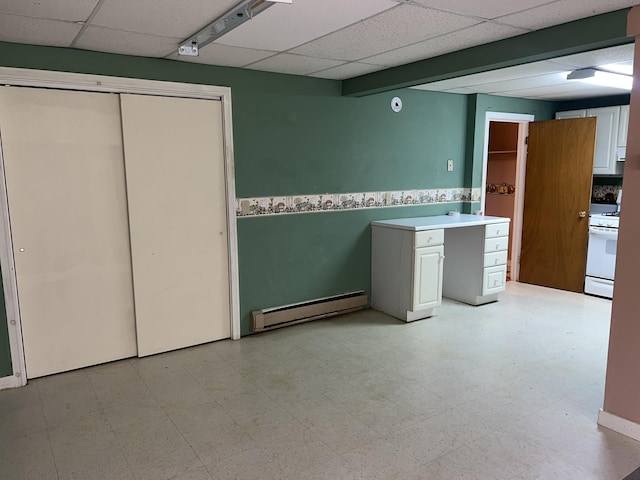 interior space with light floors, a baseboard radiator, light countertops, a paneled ceiling, and white range with gas cooktop