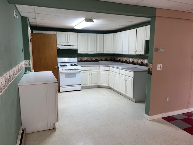 kitchen with light floors, under cabinet range hood, white cabinets, a paneled ceiling, and gas range gas stove
