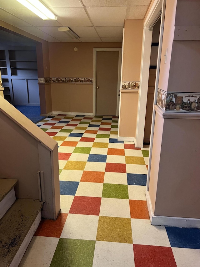 corridor featuring a paneled ceiling and light floors