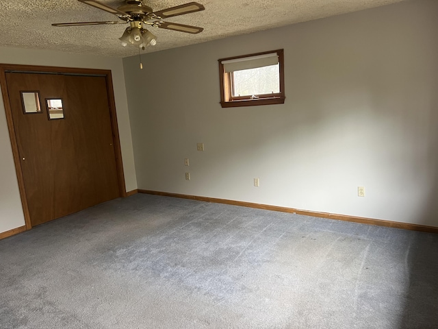 carpeted empty room with a textured ceiling, baseboards, and a ceiling fan