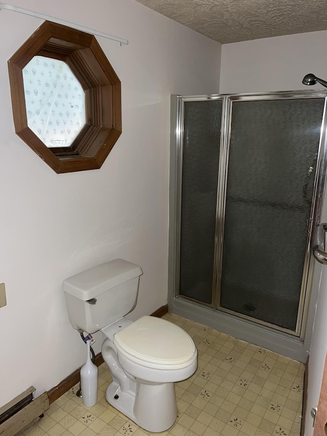 bathroom featuring a stall shower, a textured ceiling, baseboards, toilet, and tile patterned floors
