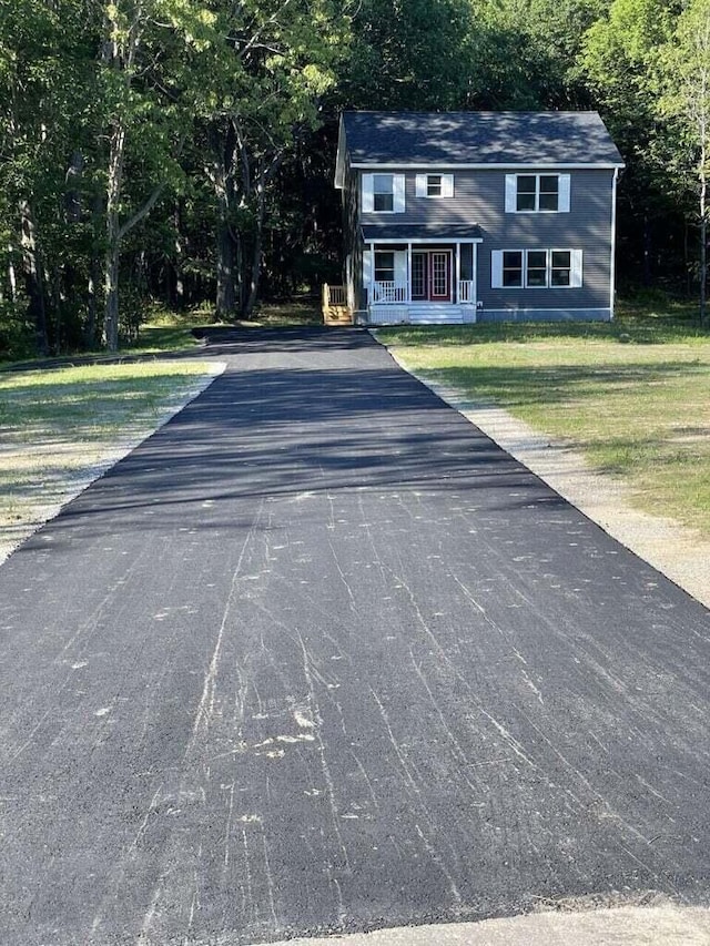 view of front of home with a front yard, covered porch, and aphalt driveway