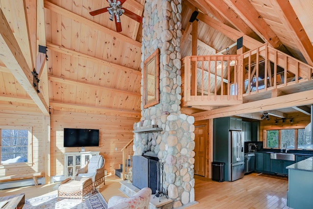 84 Ira Mountain Rd, Kingfield, ME 04947 - unfurnished living room with a sink, wooden ceiling with exposed beams, wood walls, a stone fireplace, and light wood finished floors