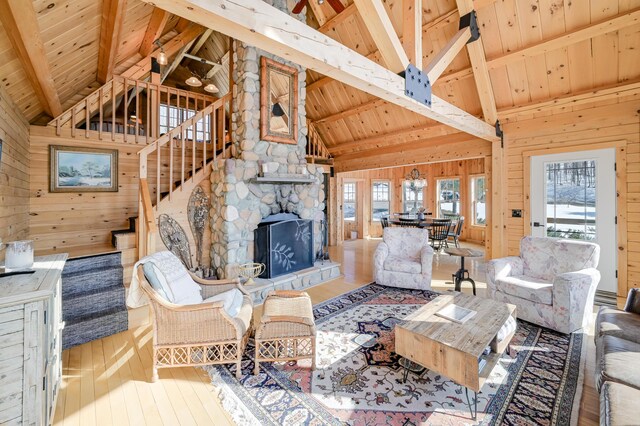 84 Ira Mountain Rd, Kingfield, ME 04947 - living area featuring wood ceiling with exposed beams, wood walls, hardwood / wood-style flooring, high vaulted ceiling, and a stone fireplace