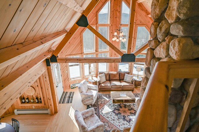 84 Ira Mountain Rd, Kingfield, ME 04947 - living area with baseboard heating, wooden walls, hardwood / wood-style flooring, a chandelier, and high vaulted ceiling