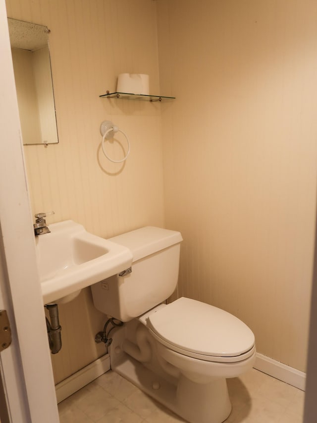 bathroom with baseboards, toilet, and tile patterned flooring