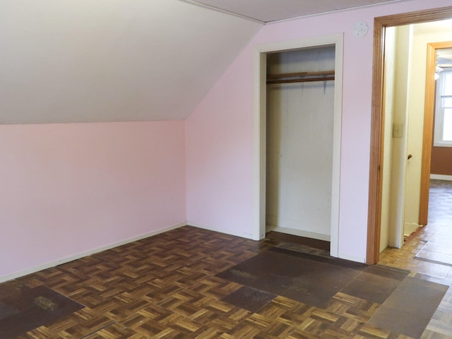 unfurnished bedroom with a closet, baseboards, and vaulted ceiling