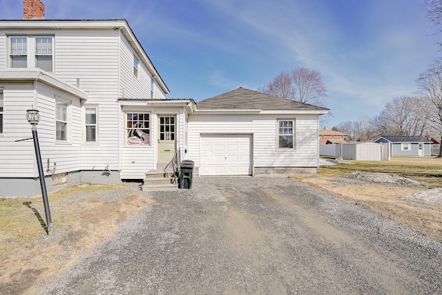 back of house featuring entry steps, a garage, and dirt driveway