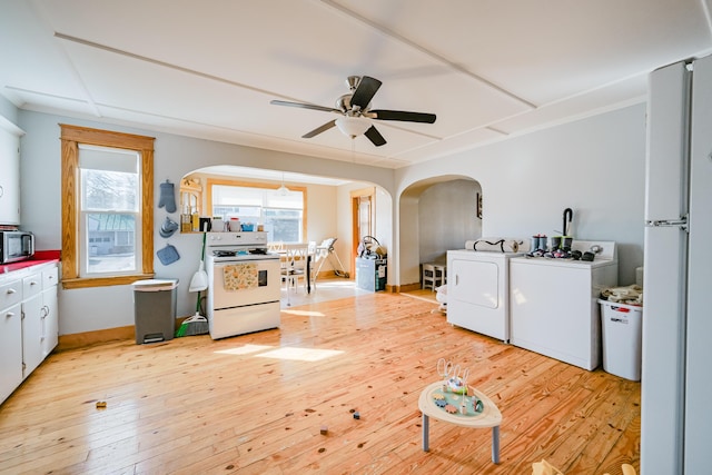 interior space with arched walkways, laundry area, a wealth of natural light, and light wood-style floors