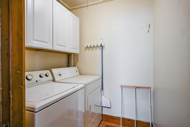 washroom featuring washer and clothes dryer, cabinet space, attic access, and light wood-style flooring