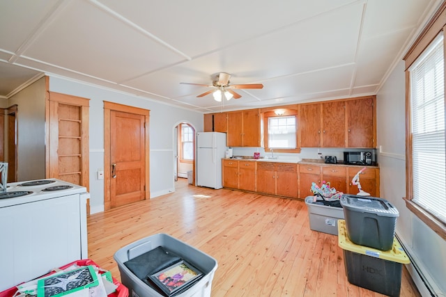 kitchen featuring brown cabinets, light wood finished floors, a ceiling fan, white appliances, and light countertops