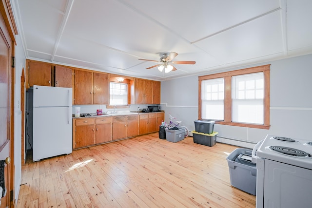 kitchen featuring light countertops, light wood-style flooring, brown cabinetry, white appliances, and a sink