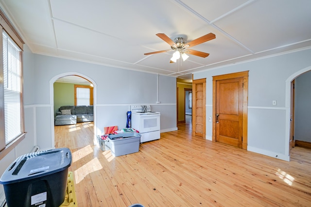 interior space with arched walkways, light wood finished floors, baseboards, and ceiling fan