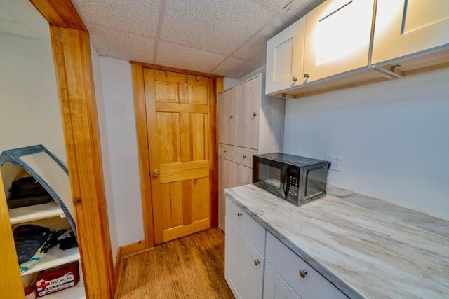 19 Glenview Ln, Belfast, ME 04915 - kitchen with black microwave, light wood-style flooring, white cabinetry, a drop ceiling, and light stone countertops