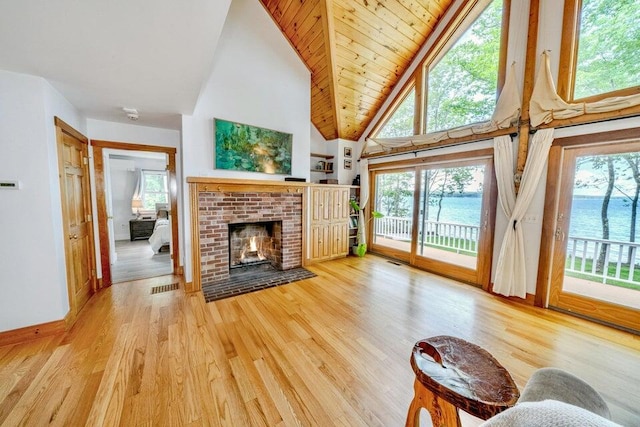 19 Glenview Ln, Belfast, ME 04915 - living area with high vaulted ceiling, healthy amount of natural light, a brick fireplace, wood finished floors, and wooden ceiling