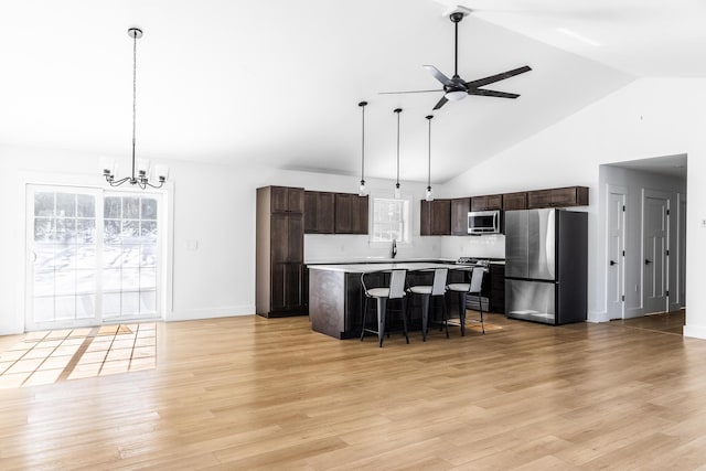 kitchen featuring dark brown cabinets, a center island, a breakfast bar, appliances with stainless steel finishes, and light wood-style floors