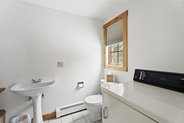 bathroom with tile patterned flooring, baseboard heating, washer / dryer, and toilet