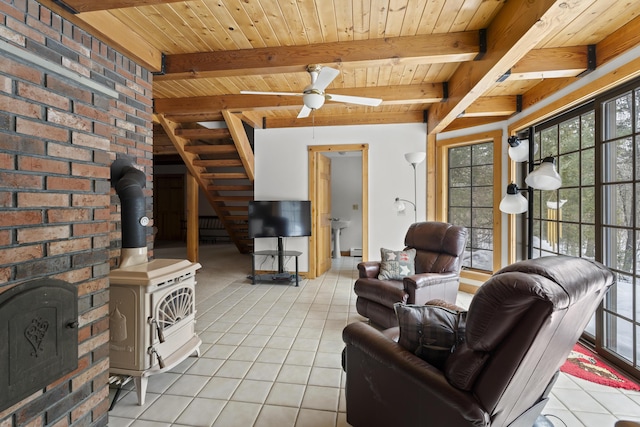 living area featuring beamed ceiling, a healthy amount of sunlight, light tile patterned flooring, and a wood stove