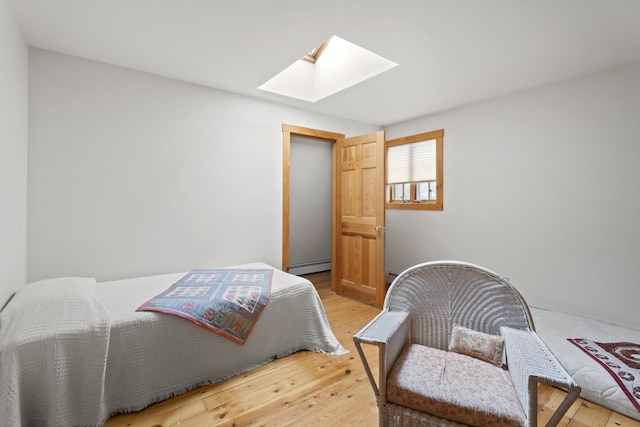 bedroom with a baseboard radiator, a skylight, and light wood finished floors