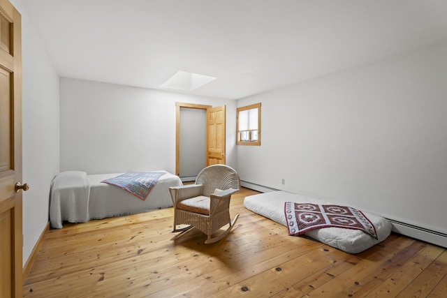 bedroom featuring hardwood / wood-style floors, a skylight, and baseboard heating
