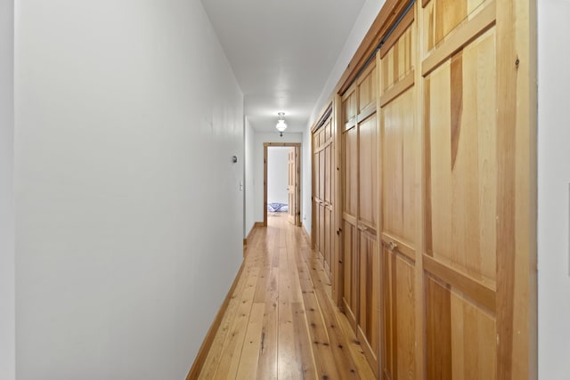 hall with light wood-style flooring and baseboards