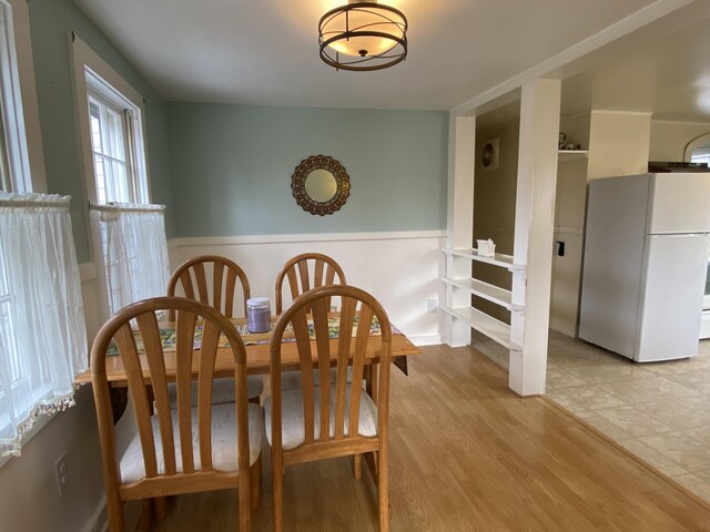 dining area featuring a wainscoted wall and light wood-type flooring