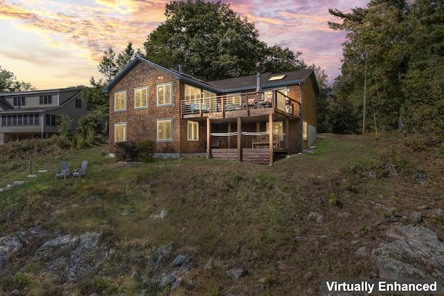 back of house at dusk featuring a deck