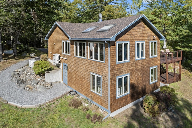 view of home's exterior featuring roof with shingles and a deck