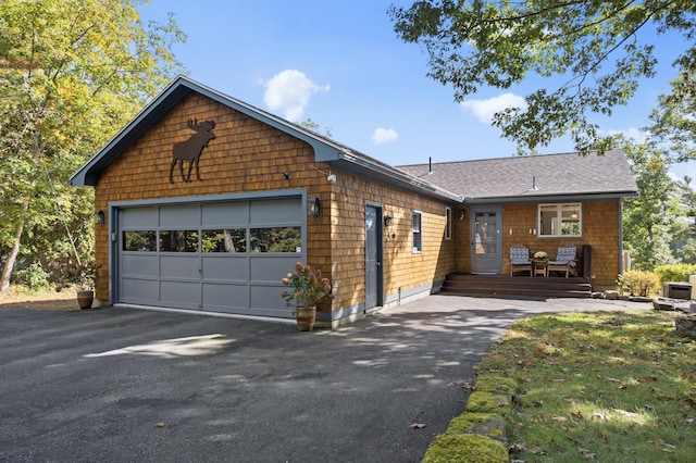 view of front of home featuring driveway, an attached garage, and a shingled roof
