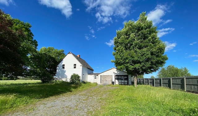 view of yard with an outbuilding, driveway, a garage, and fence