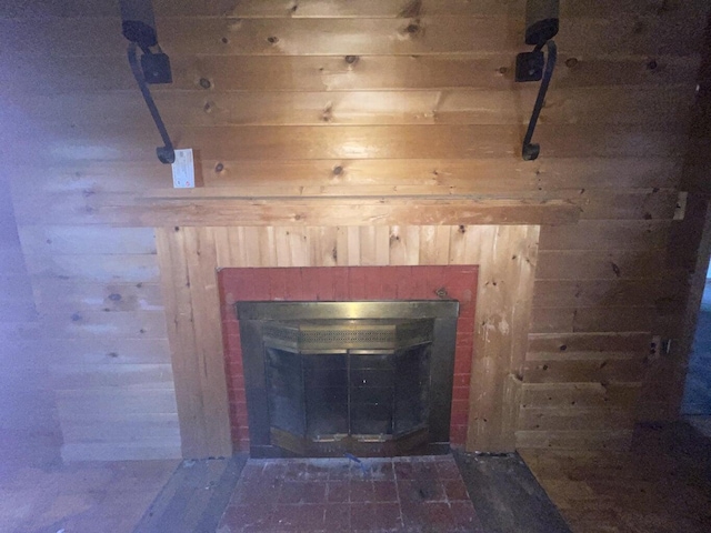 interior details featuring a brick fireplace and wood walls