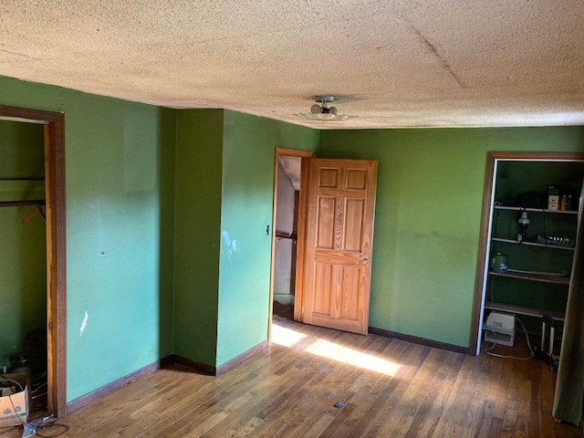 unfurnished bedroom with baseboards, a textured ceiling, and hardwood / wood-style floors