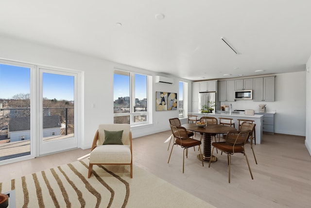 dining space with light wood-style flooring, a wealth of natural light, and a wall mounted AC