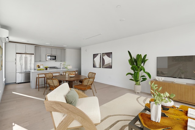 living room with a wall unit AC and light wood-style floors