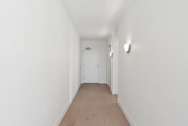 corridor featuring light wood finished floors and baseboards