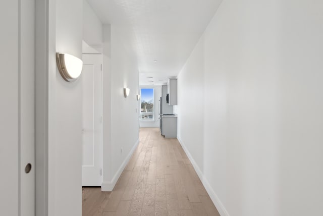 hallway featuring baseboards and light wood-style floors