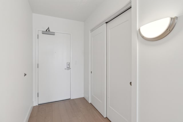 corridor with light wood-type flooring and baseboards