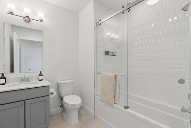 bathroom with baseboards, enclosed tub / shower combo, toilet, and vanity