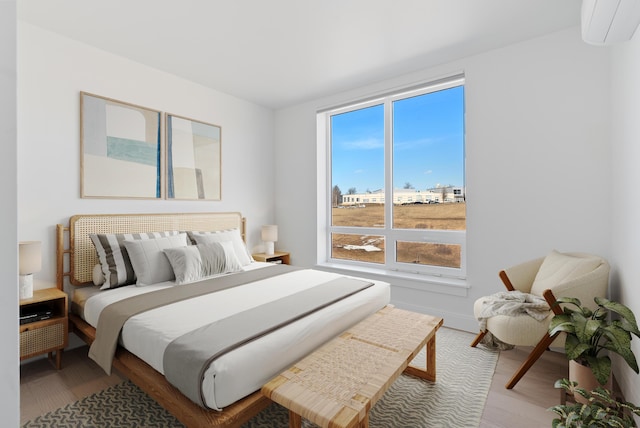 bedroom featuring a wall mounted air conditioner and wood finished floors