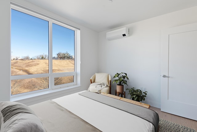 bedroom with baseboards, an AC wall unit, and wood finished floors