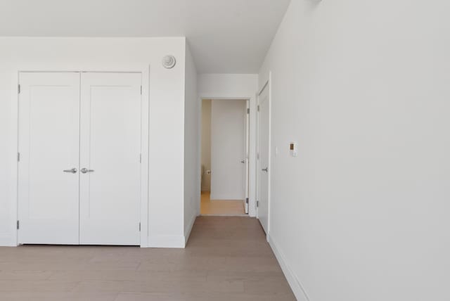 unfurnished bedroom with light wood-style floors, a closet, and baseboards