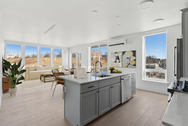 kitchen with light countertops, gray cabinets, a wall mounted air conditioner, and a sink