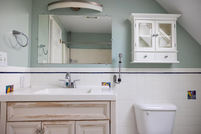 bathroom with toilet, vanity, and lofted ceiling