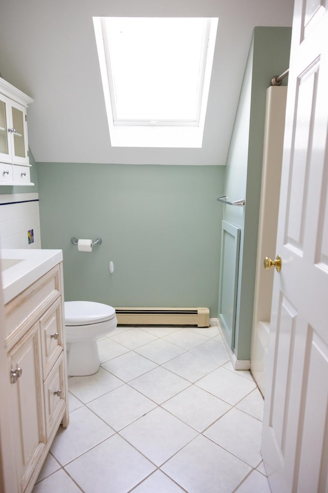 bathroom with tile patterned floors, lofted ceiling with skylight, toilet, and a baseboard radiator