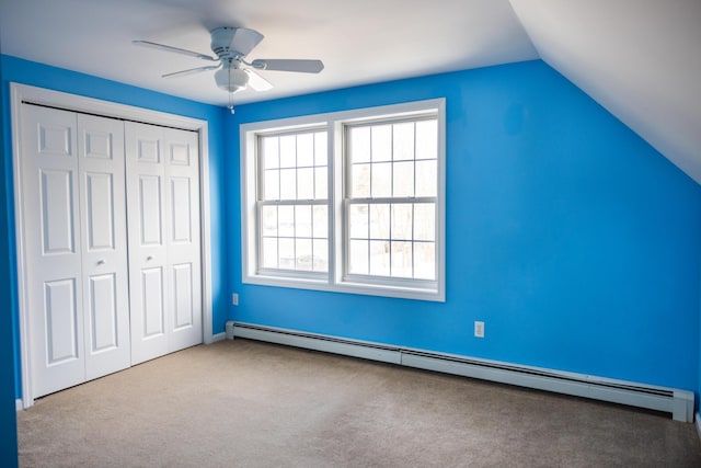 unfurnished bedroom with carpet, vaulted ceiling, a closet, a ceiling fan, and a baseboard radiator