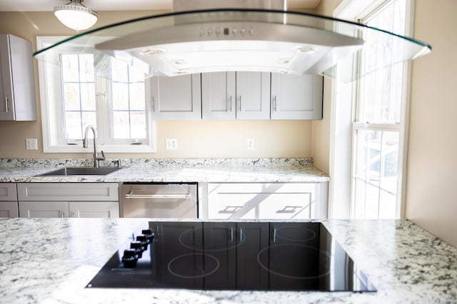 kitchen featuring dishwasher, black electric cooktop, light stone countertops, and a sink