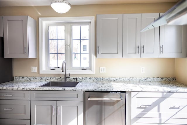 kitchen with light stone counters, gray cabinets, dishwasher, and a sink