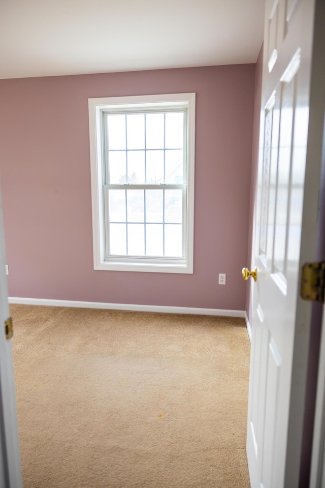 carpeted empty room featuring baseboards