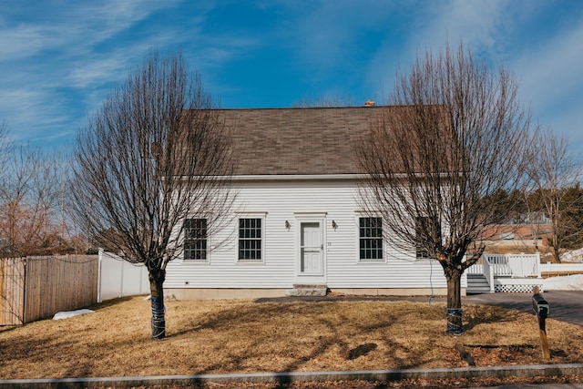 cape cod-style house with a front yard, fence, and roof with shingles