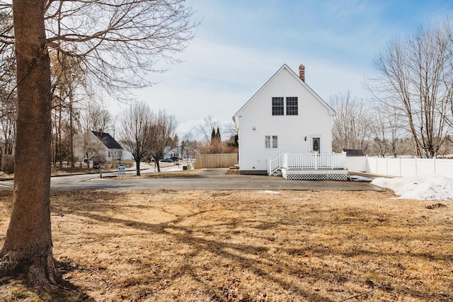 back of property featuring a wooden deck, fence, and a chimney